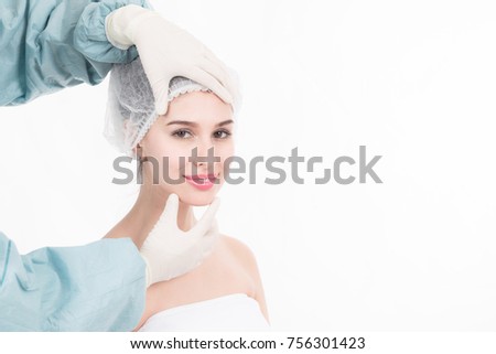 Professional plastic surgery services. Portrait of beautiful white woman face being study by female doctor to identify which area to enhance her face with surgery techniques. Isolated in white.