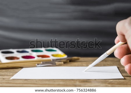 Artist painting a picture with paint brush on white sheet. Art concept. 