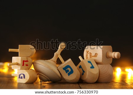 Image of jewish holiday Hanukkah with wooden dreidels collection (spinning top) and gold garland lights on the table