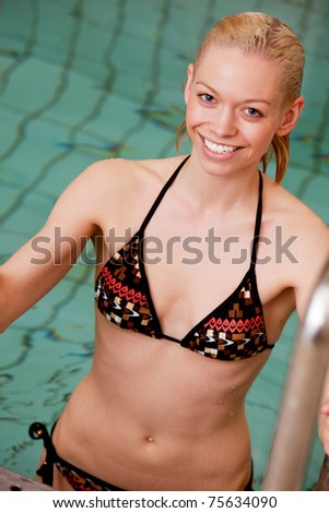 A portrait of a smiling blond woman exiting a swimming pool