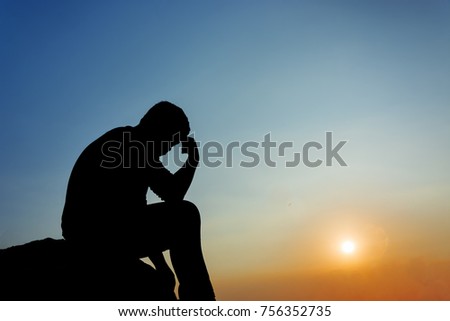 Silhouette of man sitting at sunset Royalty-Free Stock Photo #756352735