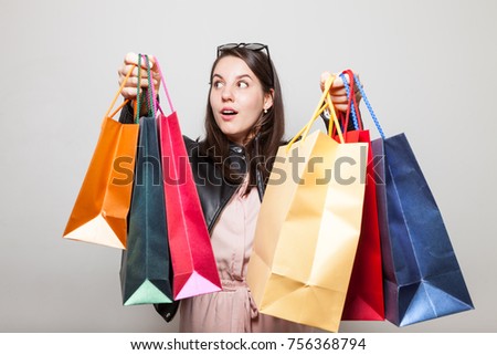 Surprised girl has hands full of gift shopping bags