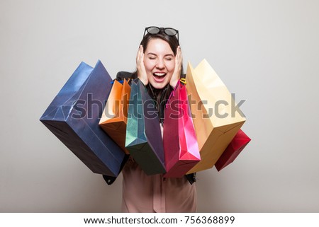 Happy shopper screams with ears closed and hoding shopping bags