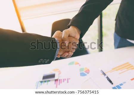 Close-up of two business people shaking hands during a meeting in the office,