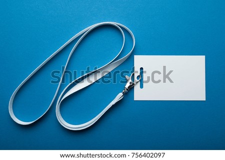 Blank business badge isolated on blue background. Plain empty name tag mock up hanging on neck with string.