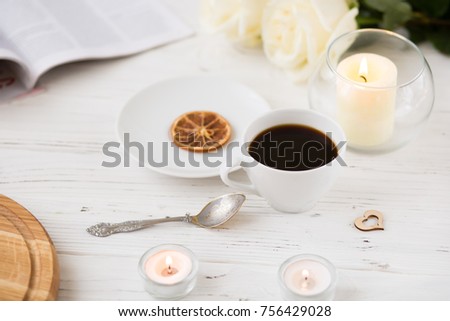 Coffee for breakfast or lunch with decorations, candles and flowers. white roses on the table and cup of coffee