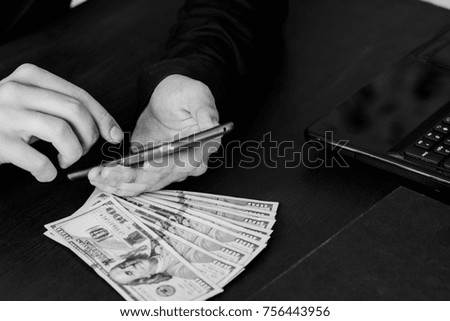 Technology, online banking, money transfer, e-commerce concept. Businessman using smartphone dollar bills flying on grey wall background. Internet earnings concept