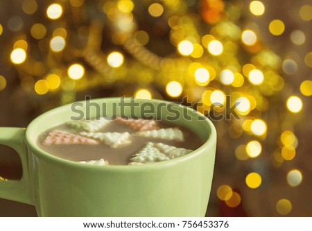 Cocoa with marshmallows on christmas tree lights  background.