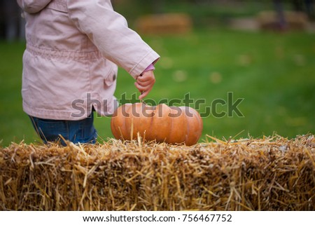 Child playing with pumpkin outdoors.