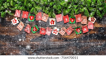 Christmas tree branches with Advent calendar on dark wooden background. Vintage style toned picture with falling snow