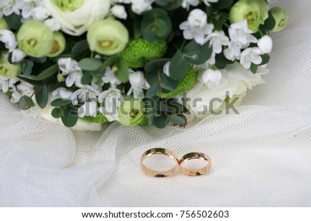 Wedding rings and bride bouquet flowers green white background