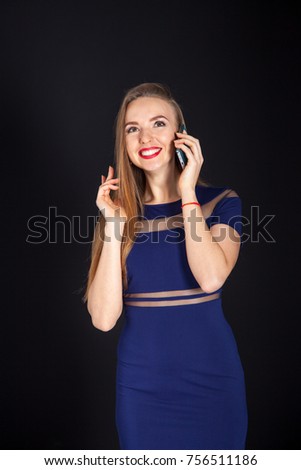 Photo shoot beautiful blonde woman in navy blue dress on black studio backdrop with mobile phone.