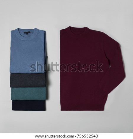 Beautiful set, luxurious, knitted woolen sweater folded, burgundy, blue, green, autumnal, winter, warm, layout on a gray background