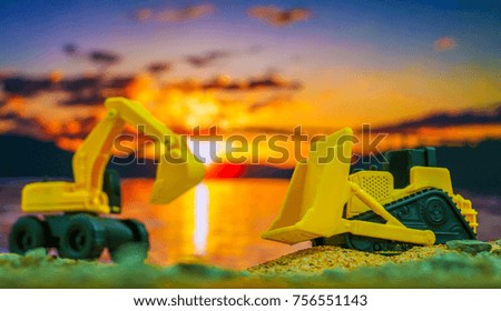 Construction engineering concept , Excavator machine toy and Truck toy working on construction field with silhouette sunset background