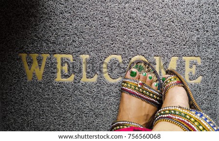 standing on welcome written doormat