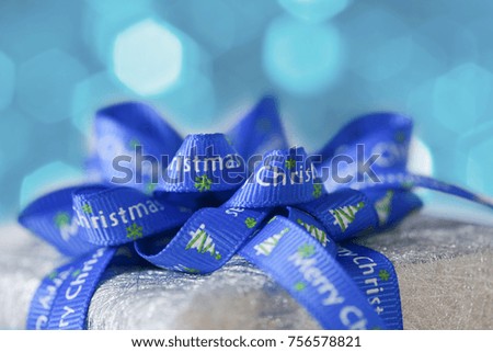 Christmas gift with Christmas wording ribbon on blue brokeh background
