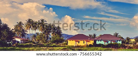 Panoramic landscape of houses surrounded by trees with background of evening sky. Colorful asian houses. Langkawi island, Malaysia. Instagram color editing.