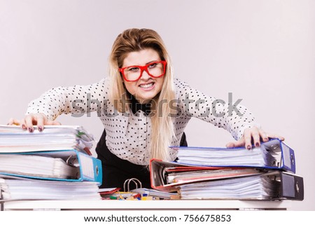 Happy business woman feeling energetic sitting working at desk full off documents in binders.