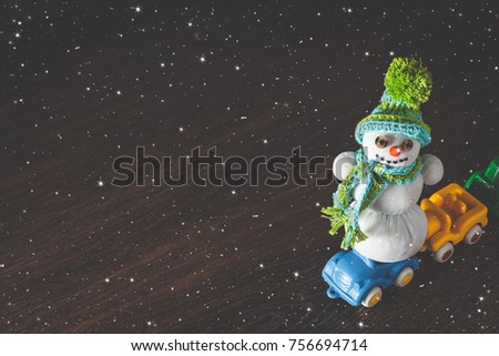 Merry christmas and happy new year greeting card with copy space. xmas snowman on red toy model car. Snow background