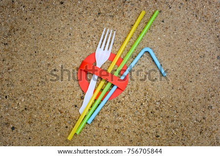 A creative artwork of stop sign over plastic fork and straws on sandy beach background urging people not to use these items to prevent marine pollution. Ban single use plastic.