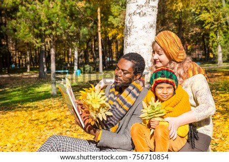 Happy family in autumn park. African American family: black father, mom and child boy on nature in fall.