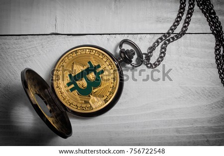 Photo of an old-fashioned opened bitcoin watch laying on white wooden table surface.