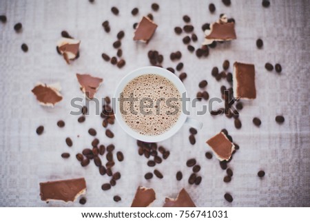 Cup of coffee and beans, chocolate, cookie on linen tablecloth