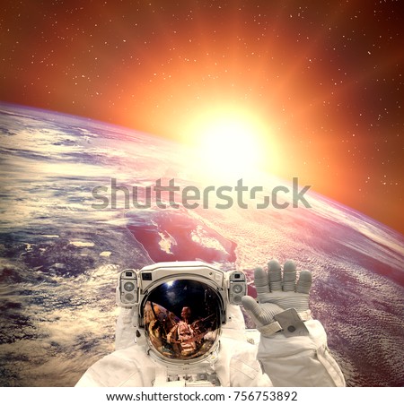 Astronaut waving against the sunrise on earth. The elements of this image furnished by NASA.
