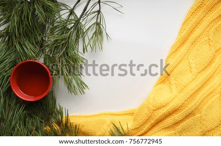Christmas background with a Cup  of tea,  branches of pine with large needles and a yellow sweater. Top view, close-up 