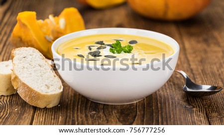 Portion of fresh made Pumpkin Soup (close-up shot) on rustic background