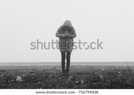 Woman with retro camera in a fog landscape