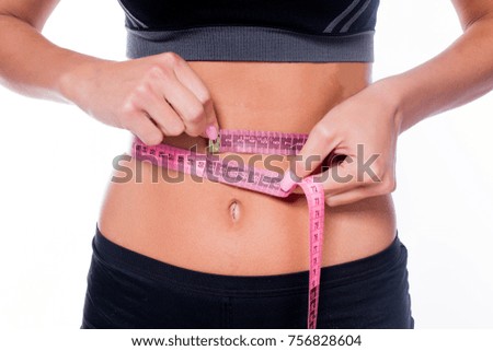 A beautiful young sports body girl measures the waist size