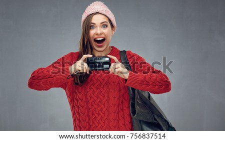 Happy girl tourist holding photo camera. woman traveler portrait on gray wall back.