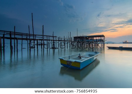 the serene surrounding of an old jetty during sunrise. The image may contain soft and blurry subjects due to long exposure