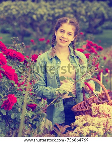 smiling english female posing near roses and holding a basket in the garden