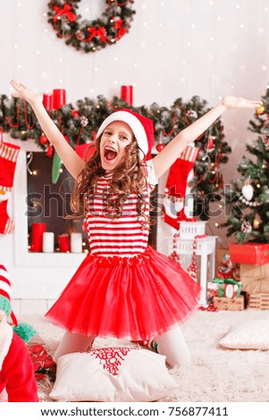 cheerful girl in a new costume by the fireplace and Christmas tree

