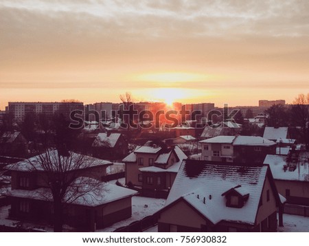 Sunrise in early morning. Vintage filter effect. The sun's rays shine over the roofs of the house. North cold winters. (Latvia).