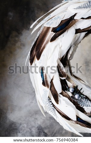 Christmas wreath of white and brown feathers on a gray background with divorces