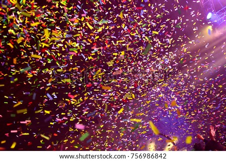 Confetti fired on air during a concert. People are happy and with hands in the air. Image ideal for backgrounds. Multicolor are the confetti in the picture