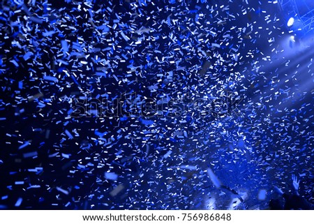 Confetti fired on air during a concert. People are happy with hands in the air. Image ideal for backgrounds. Blue is the tone of the picture