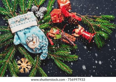 Christmas tree and Christmas tree decorations covered by snow on black wooden surface, and Merry Christmas and Happy New Year. Top view, free space, flat lay. Toned