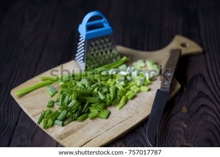 sliced green onions, knife and grater on a wooden table