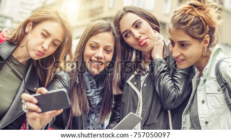 Happy girl friends taking selfie photos in the street. Internet and social media