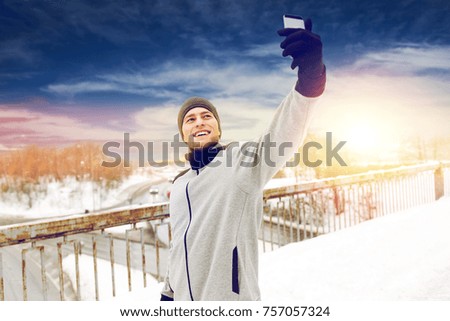 fitness, sport, people, exercising and healthy lifestyle concept - young man taking selfie with smartphone in winter 