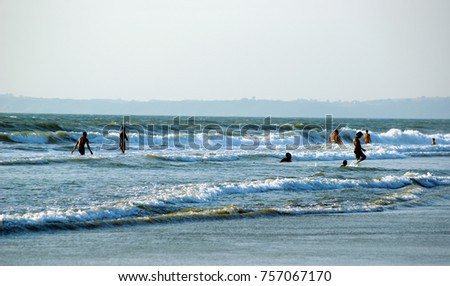 Tourists enjoying  and frolicking in the cool and safe waters of a south Goa beach. Copy space