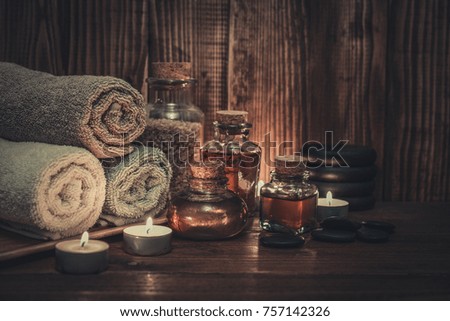 Towels with sea salt, massage oil in vintage bottle, candles and stones for stone massage on wooden background