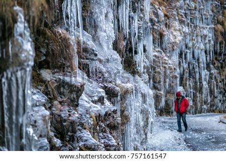 Young men walking through an ice road with stalactites hanging from the rocs.