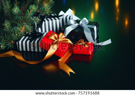 Gift boxes with bows and spruce branch for Christmas holidays, on a dark background, with a reflection of colored lights, template for greeting cards, invitation cards.