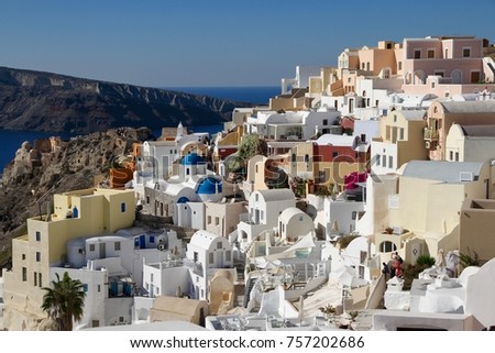 A view of colorful cubiform buildings on Santorini Island in Greece clinging to the cliff over the Aegean Sea.  Royalty-Free Stock Photo #757202686