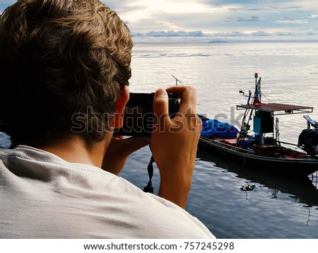 Backside of man taking photo of boat in the sea, dicut concept.